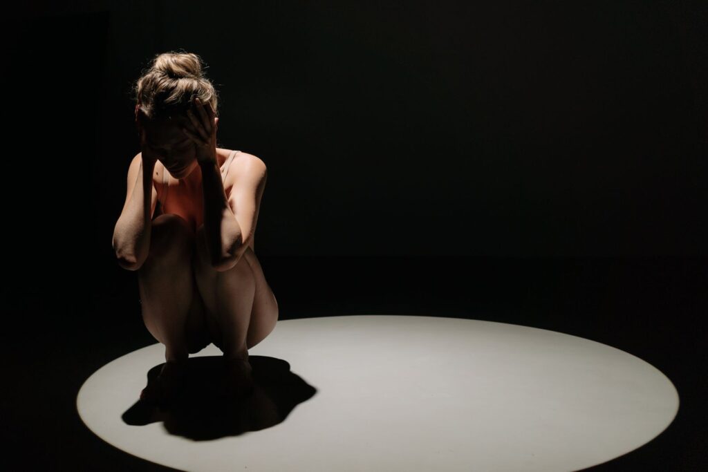 Woman alone under a spotlight in a dark room