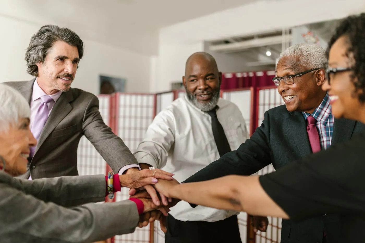 Older adults joining hands in a group therapy session