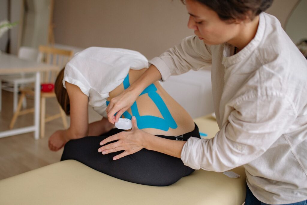 Therapist applying kinesiology tape to a patient’s back for pain relief