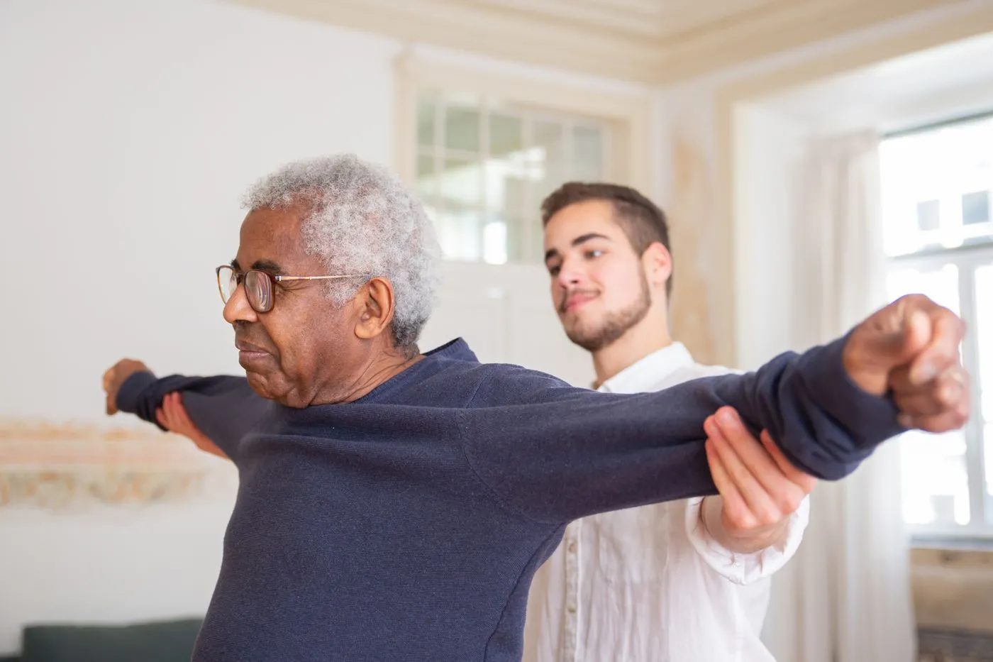 Older man stretching his arms with his physical therapist