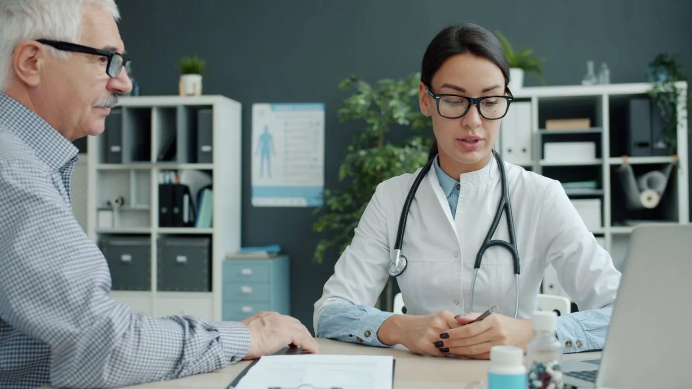 Older man talking with his doctor in a bright consultation room